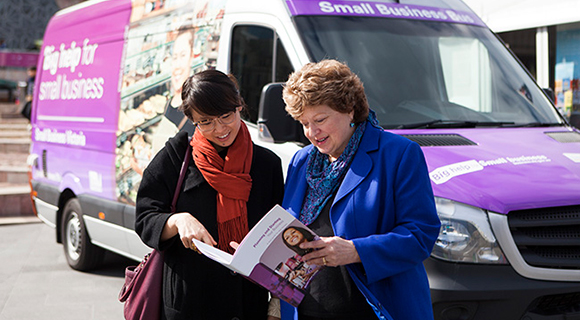 two business owners in front of the small business bus